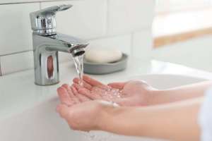 person rinsing their hands at the sink with water 1