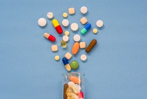 Pílulas e cápsulas de remédio espalhadas em uma superfície azul