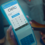Mão segurando maquininha da Cielo