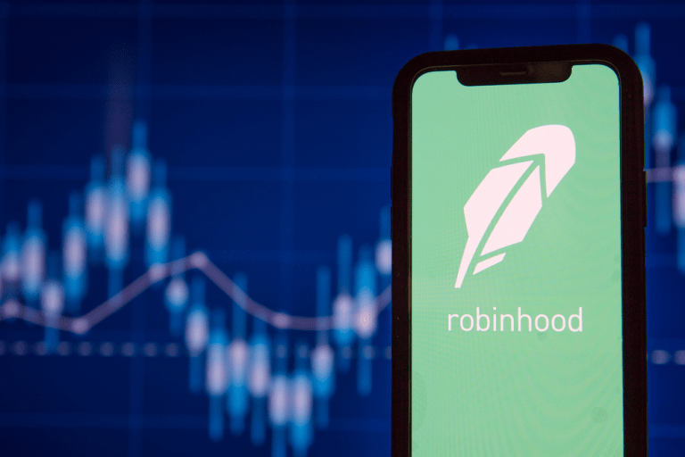 Foto de celular aberto no aplicativo da Robihood, com foco no logo e gráfico de preço de ações ao fundo