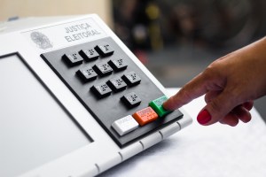 pessoa aperta botão de confirma em urna eletrônica