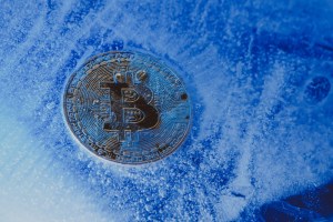 Um moeda com o símbolo do Bitcoin enterrada em um bloco de gelo