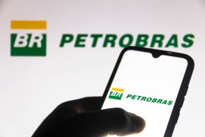 logotipos da Petrobras em celular segurado por homem e em tela de computador