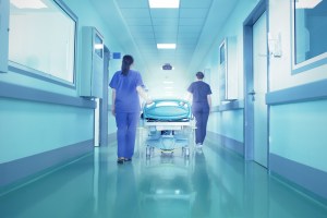 Foto de enfermeiras empurrando maca em corredor de hospital