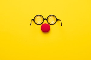 Óculo de grau e um nariz vermelho de palhaço com um fundo amarelo