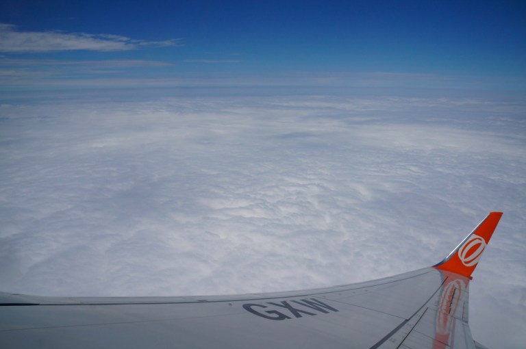 Foto de asa de avião da Gol com céu com nuvens ao fundo