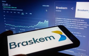 celular exibe logotipo da Braskem com tela ao fundo mostrando evolução das cotações da empresa