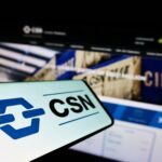 Tela de computador aberta no site da CSN e celular com a logo da companhia.