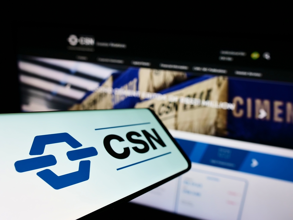 Tela de computador aberta no site da CSN e celular com a logo da companhia.