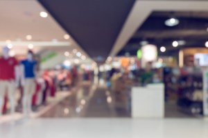 Imagem desfocada de um corredor de shopping, com uma loja do lado direito e um balcão do esquerdo.