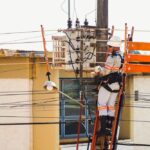 Técnico em escada para instalação de energia elétrica