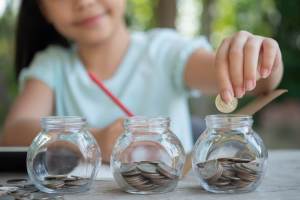 Menina colocando moedas em potes de vidro