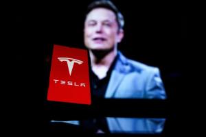 Celular com o Logo da Tesla e foto de Elon Musk no fundo