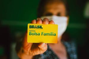 Mulher segura cartão do Bolsa Família